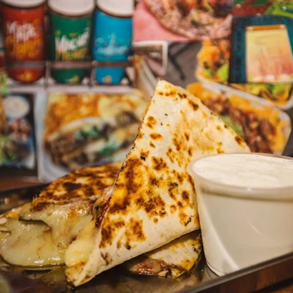 Shreddy's Tacos quesadillas with melted cheese and a side of sour cream.