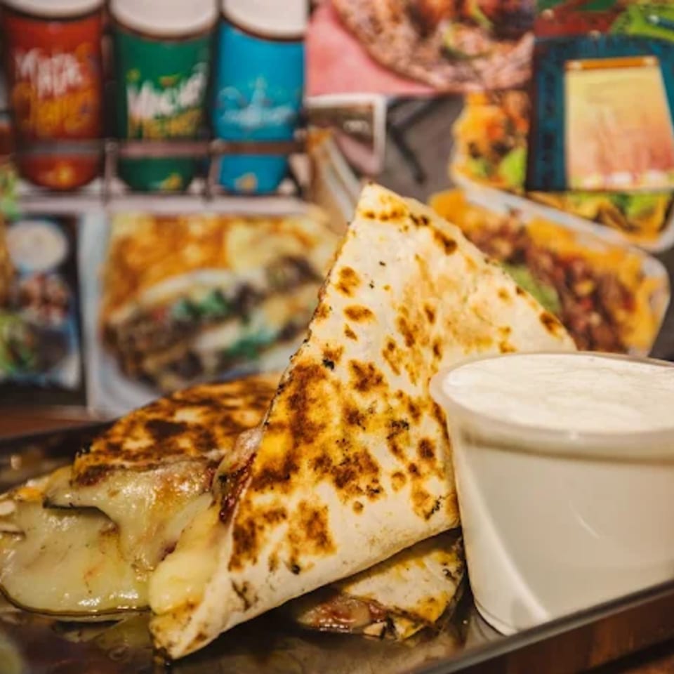 Shreddy's Tacos quesadillas with melted cheese and a side of sour cream.