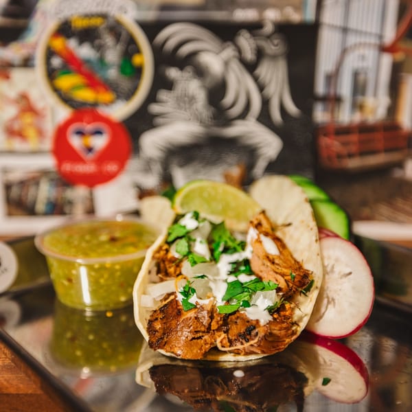 Shreddy's Tacos: a single taco with meat, cilantro, and sour cream, with salsa and radishes.